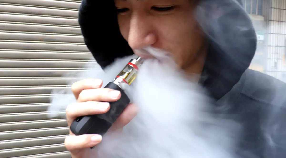 Țigara electronică cu vapori de erecție, pe bază de Viagra... "Made in China". Un bărbat cu hanorac și glugă pe cap, folosește o țigară electronică