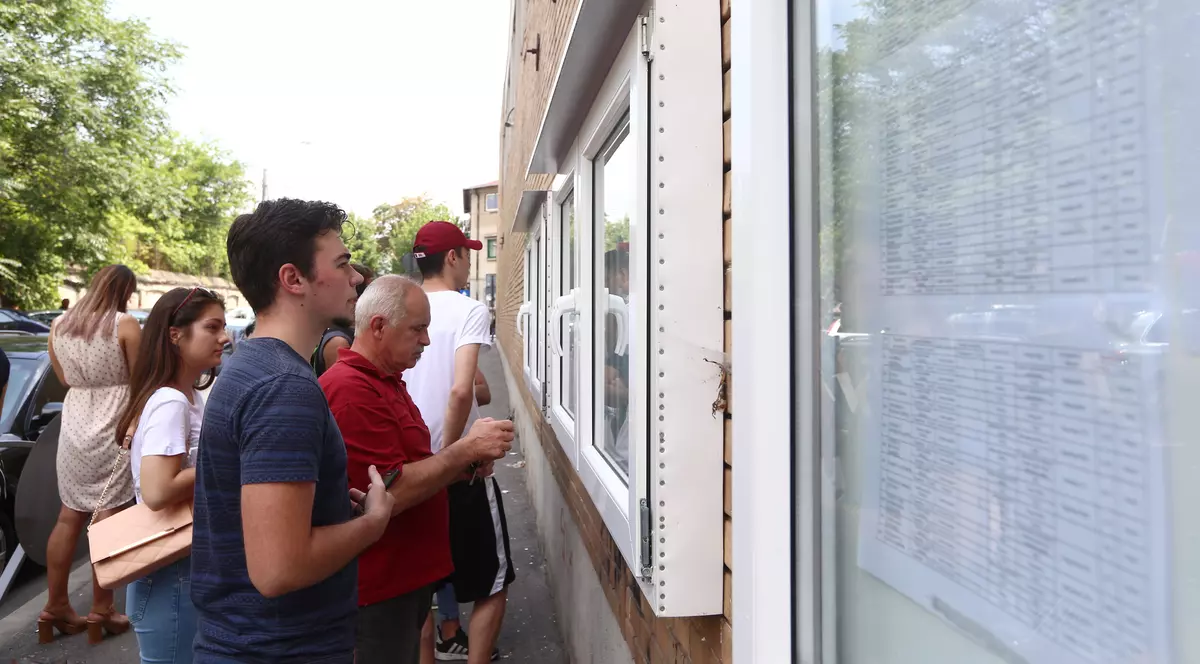 REZULTATE CONTESTAȚII BAC 2018. Numărul mediilor de 10 a crescut la 132. Mai mulți elevi consultă panoul cu rezultate, de la liceul unde au învățat