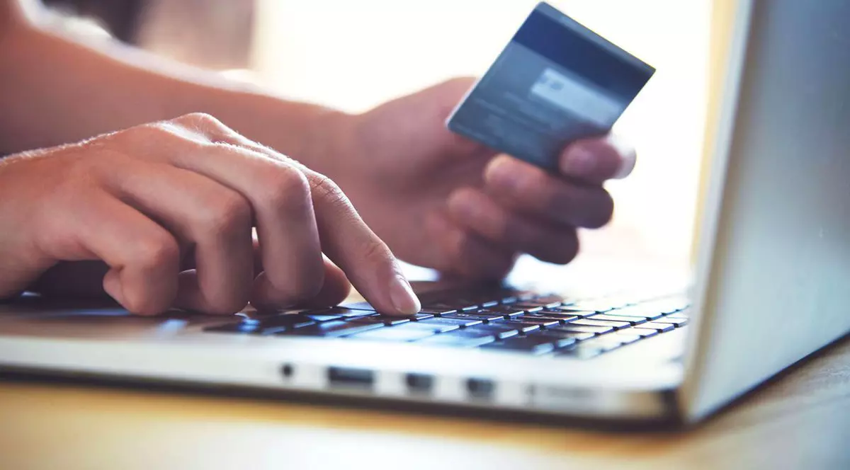 România este pe ultimul loc în UE la achizițiile online. O persoană care face o plată cu cardul bancar, de pe un laptop