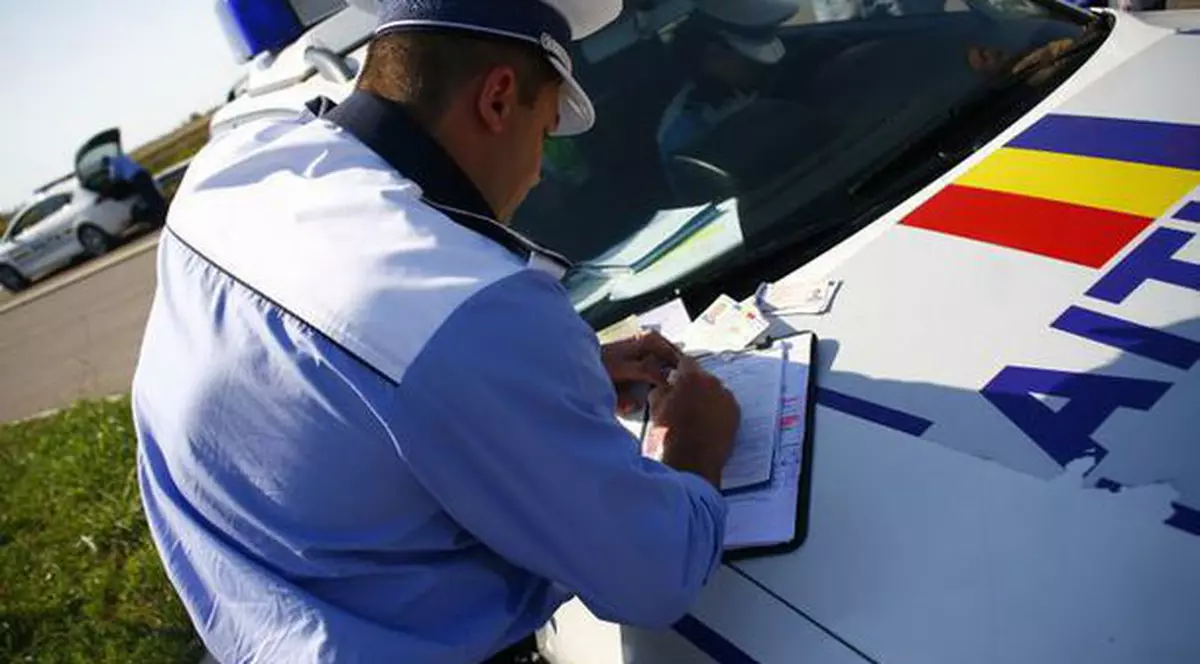 MAI a scos la concurs peste 500 de posturi. Polițist rutier care dă o amendă unui șofer, pe capota mașinii de poliție