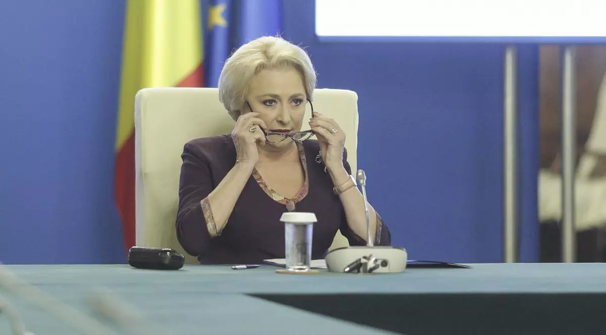 A doua rectificare bugetară din 2018. Bancnote românești, în mâna unui om. Viorica Dăncilă. la o ședință de Guvern