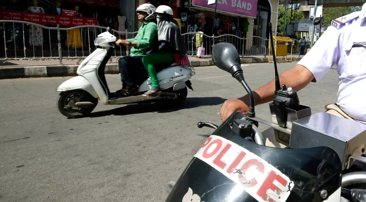 O fetiță din India a fost violată cu un furtun. Scuter de Poliție, în India, pe lângă care mai trece un al scuter, civil, cu doi pasageri