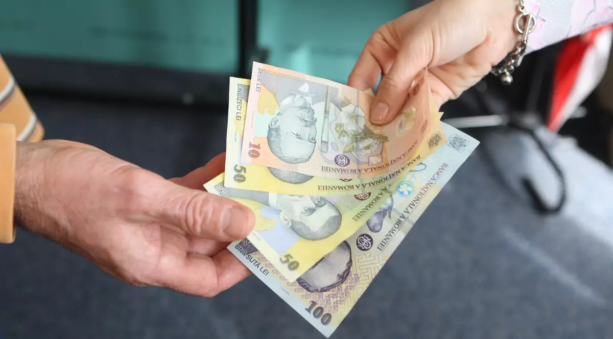 Guvernul face economie cu ”taxa pe lăcomie” chiar dacă dobânzile scad. Dou[ persoane care dau și iau bani