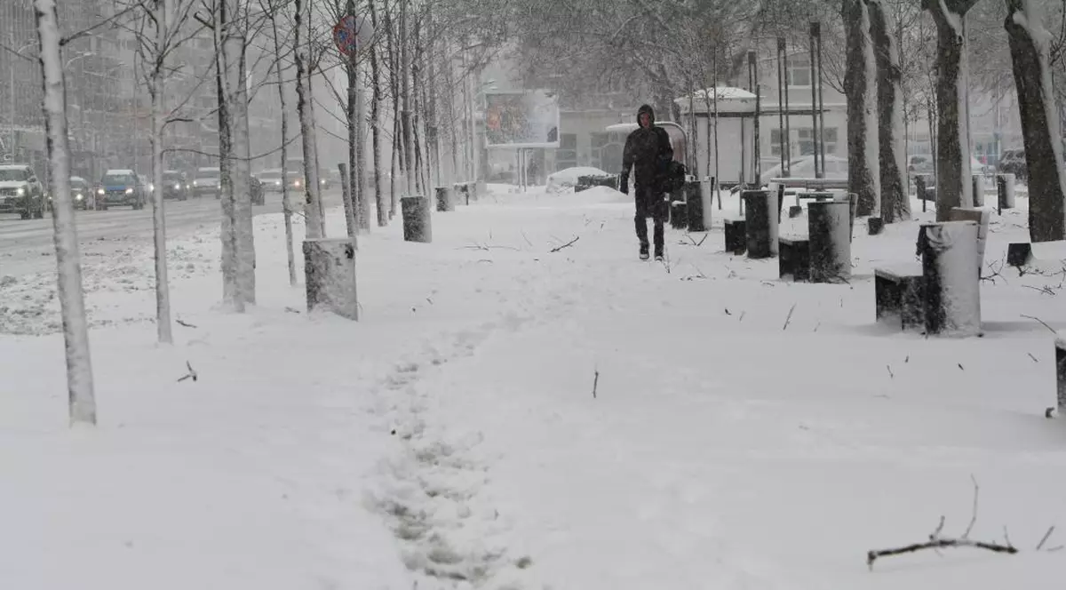 Prognoza meteo pentru 18 decembrie. Zăpadă pe trotuar, cu un om în depărtare