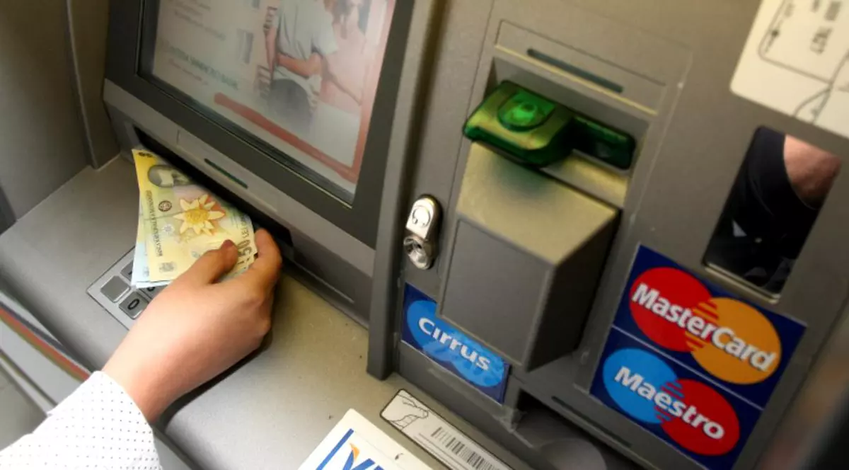 Un bărbat din Botoşani a furat cardul unui coleg. O persoană scoate bani dintr-un bancomat