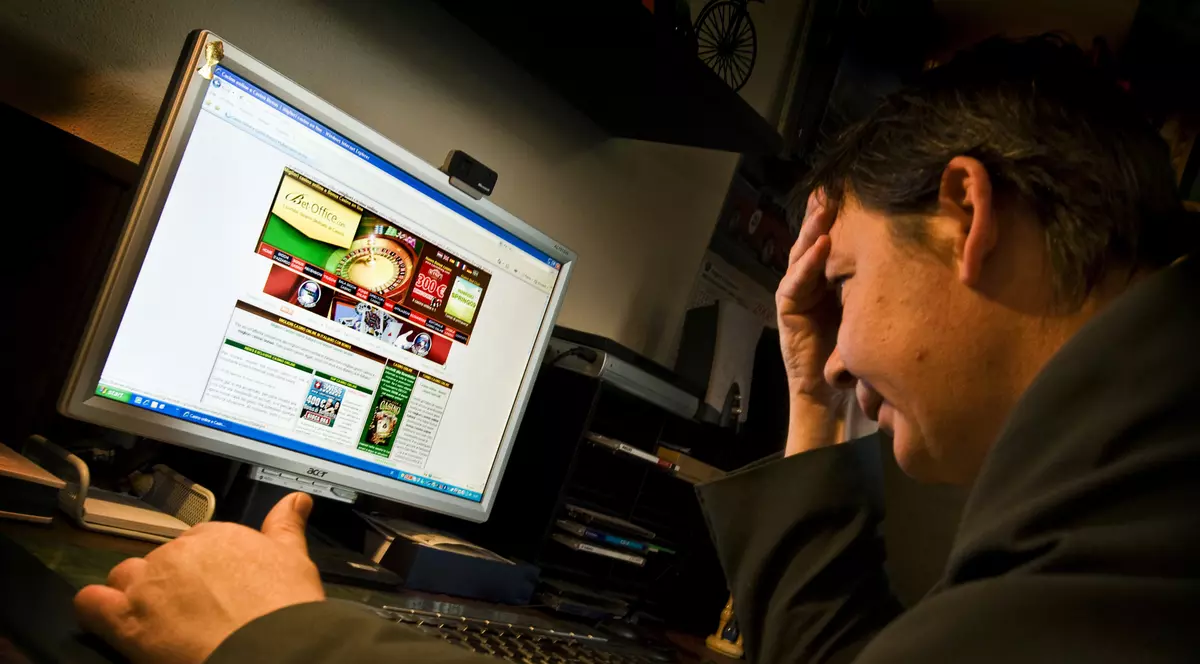 Persoană care stă în fața unui calculator și pariază pe jocuri