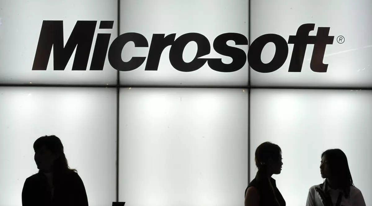 După Apple, a venit rândul Microsoft să avertizeze asupra efectelor epidemiei de coronavirus: gigantul american a anunțat că vânzările pentru sistemul de operare Windows și divizia sa de PC-uri nu se vor ridica la nivelul anterior. Logo Microsoft luminat, cu trei siluete de oameni în față