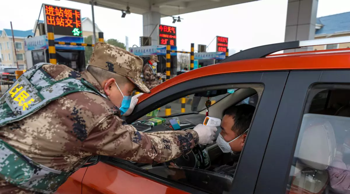 Un polițist verifică temperatura unui șofer, în Wuhan, China, orașul intrat în carantină din cauza epidemiei FOTO: EPA