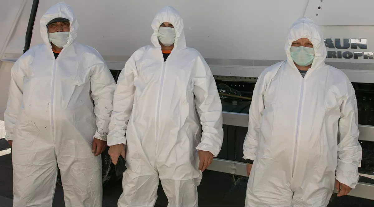 De la stânga la dreapta: Stelian, George și Relu, echipați cu combinezoane și măști de protecție