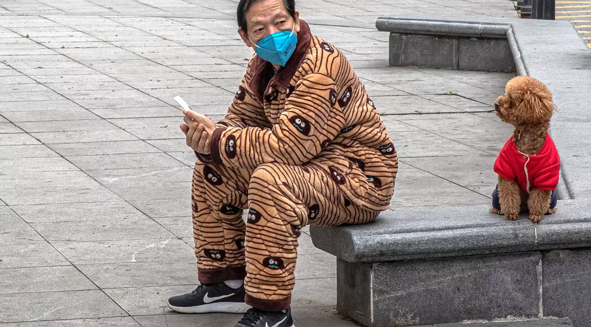 Pandemia de coronavirus schimbă lumea. În China, câinii devin prin lege animale de companie, nu de consum. Imaginea acestui chinez și a animalului său de companie a fost surprinssă chiar la Wuhan EPA-EFE