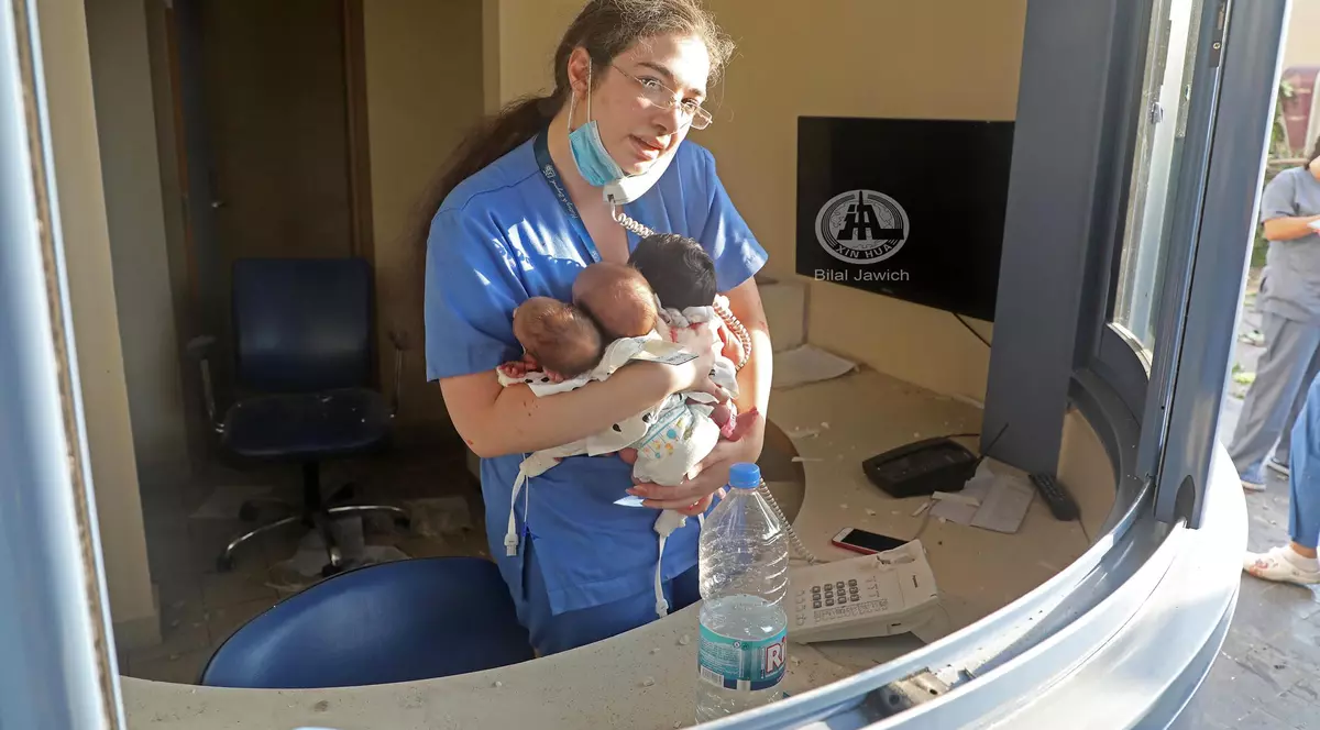 O asistentă strânge în brațe trei nou-născuți, în timpul exploziei