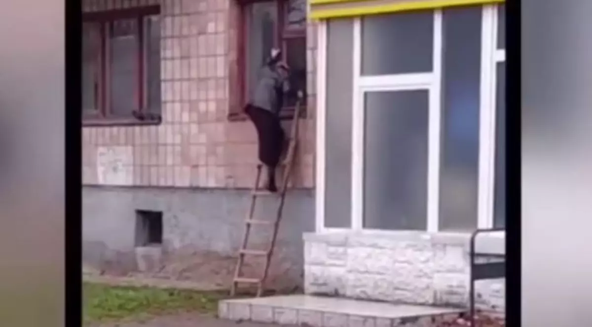 O bunicuță din Ucraina iese din bloc pe geam, cu scara, după ce la intrare a fost instalat un interfon