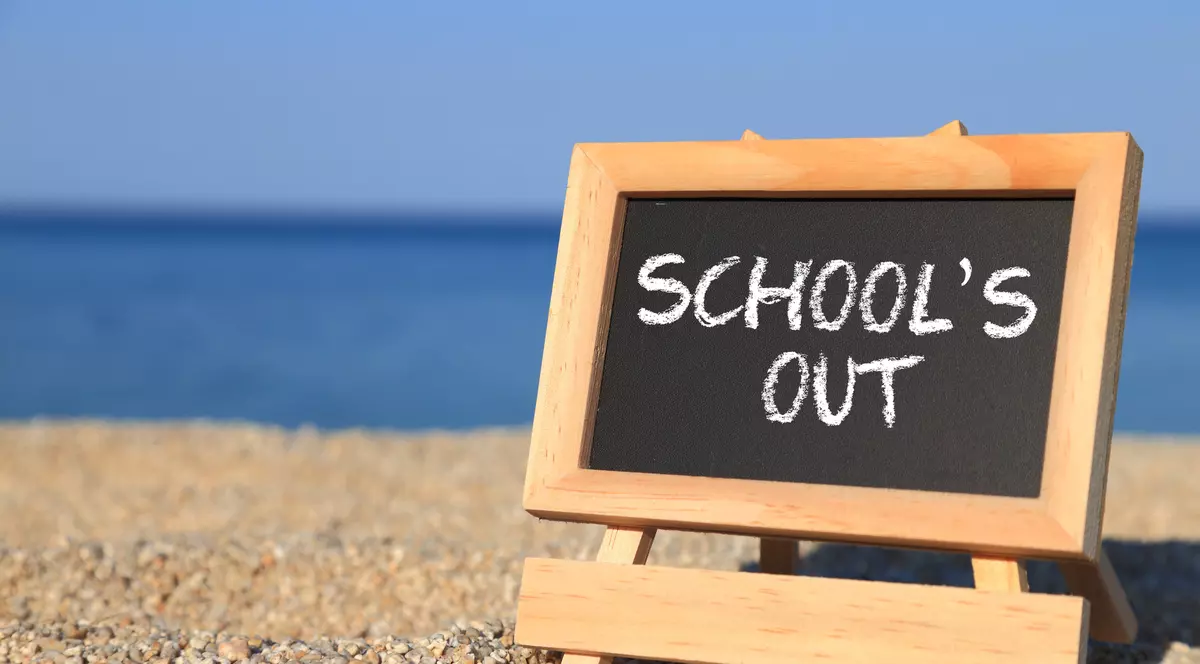 vacanta de vara 2022 - tablă cu "şcoala s-a terminat" pe o plajă