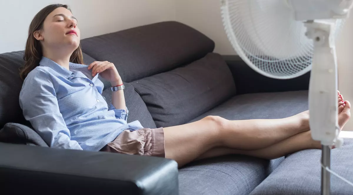 Cele mai bune ventilatoare sub 500 de lei- O femeie sta pe canapea in fata unui ventilator