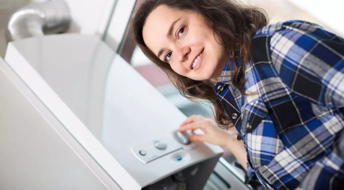 Top 10 boilere electrice ca să nu depinzi de apa caldă de la stat - Imagine cu o tânără care reglează un boiler electric
