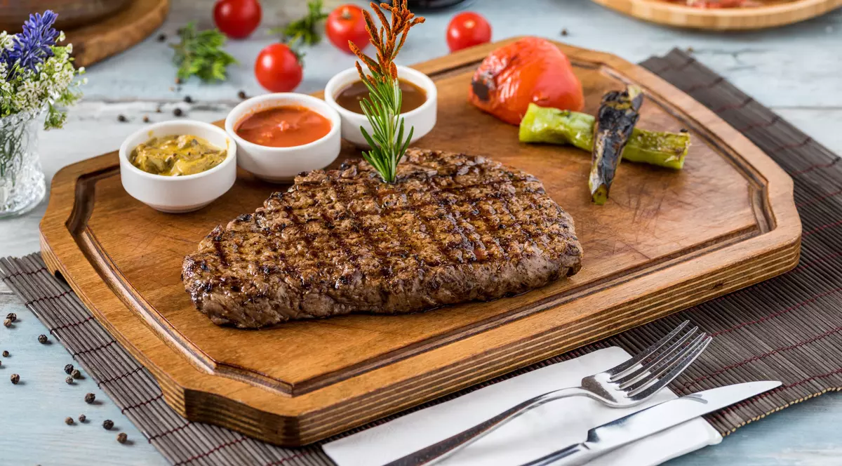 Ce mai scumpe tipuri de carne din lume- O friptura pusa pe un fund de lemn alaturi de mai multe sosuri