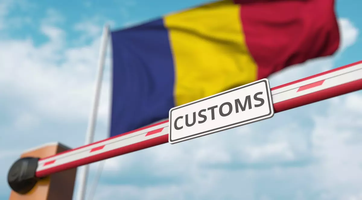 Câte puncte de trecere a frontierei are România cu statele vecine - Imagine cu o barieră pe care scrie customs, având în spate blurat drapelul României