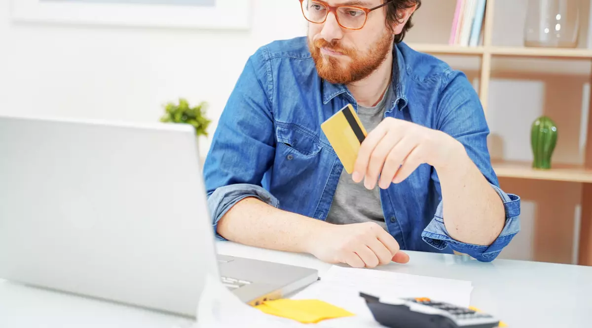 Ce este Ghiseul.ro - Imagine cu un bărbat care se află în faţa laptopului său, ţinând în mână un card bancar