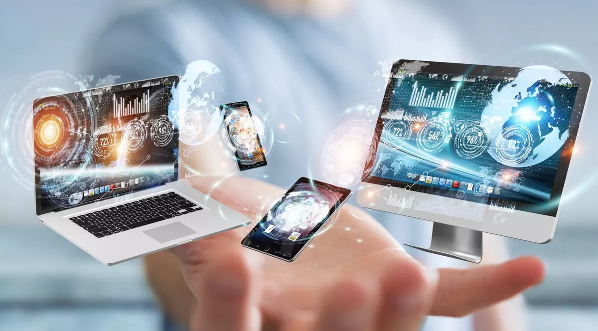 Cum conectezi telefonul cu laptopul sau cu PC-ul - Un om de afaceri pe fundal blurat, cu o mână întinsă către un computer, un monitor şi un laptop, imagine care sugerează conectarea dispozitivelor de tehnologie de redare 3D