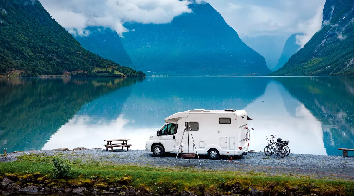 Vacanța cu autorulota - Imagine cu o rulotă parcată într-un decor de vis din Norvegia, pe malul unui lac mărginit de munţi