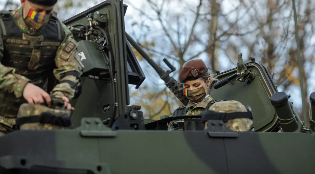 Cum poți să te înrolezi în Armata Română - Imagine cu un bărbat şi o femeie, soldaţi în Armata Română, într-un vehicul blindat, la defilarea de 1 decembrie 2021.