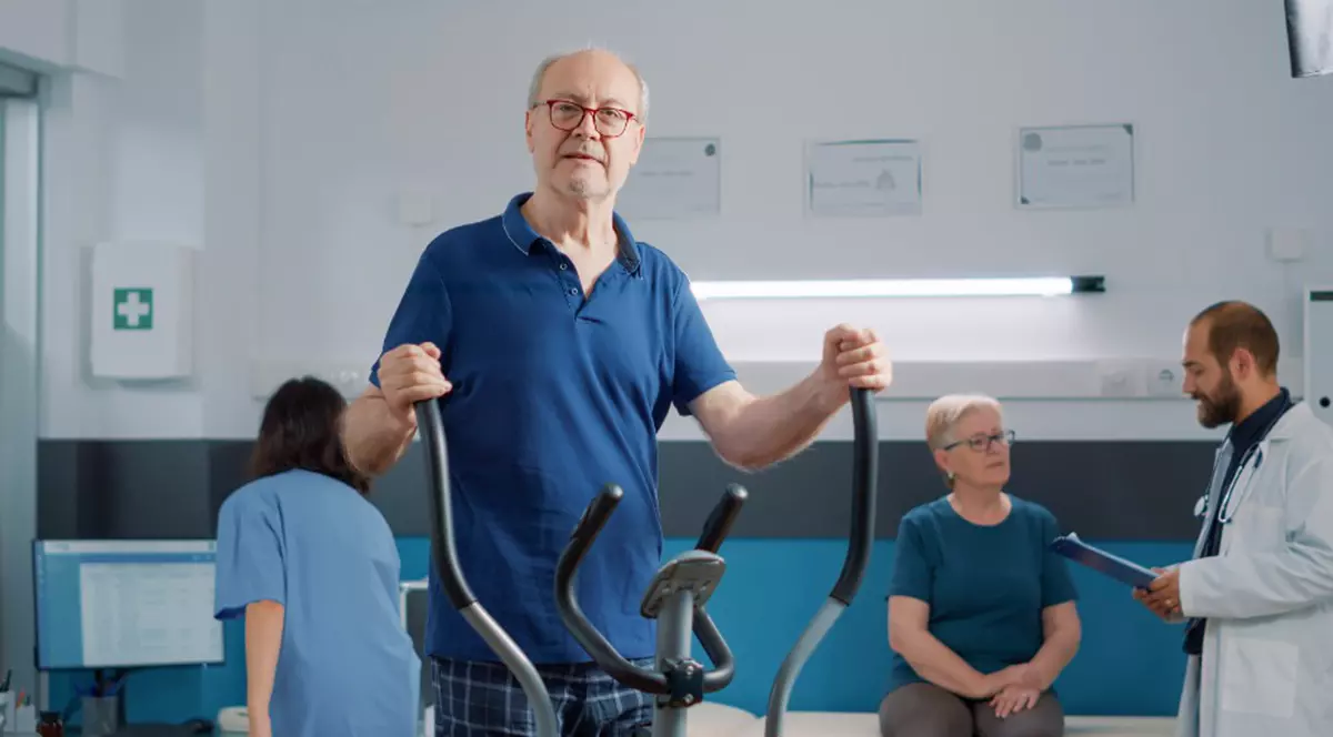 Reduceri importante la produsele de sănătate în oferta Aloshop de azi, 23 noiembrie - Imagine cu un bărbat în vârstă care efctuează exerciţii la o bicicletă eliptică, într-un centru medical