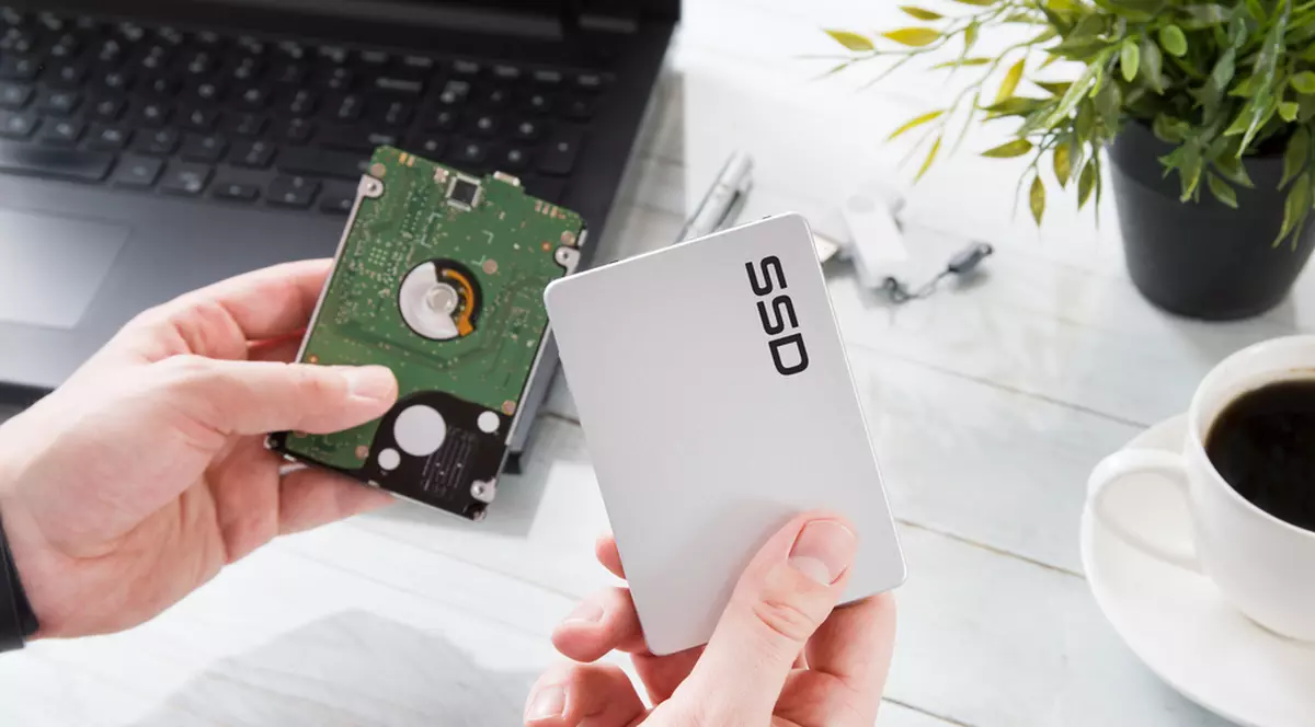 Memorii HDD şi SSD în oferta eMAG de Black Friday 2022 - Bărbat care ţine într-o mână un Hard Disk şi în cealaltă o memorie SSD