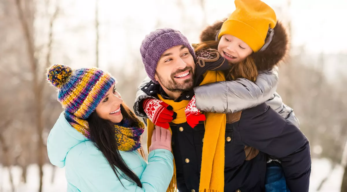 Reduceri la articole vestimentare Leviʼs în oferta Fashion Days de azi, 8 decembrie Imagine cu o tânără familie, formată din soţ, soţie şi o fetiţă, îmbrăcaţi de iarnă şi jucându-se în natură