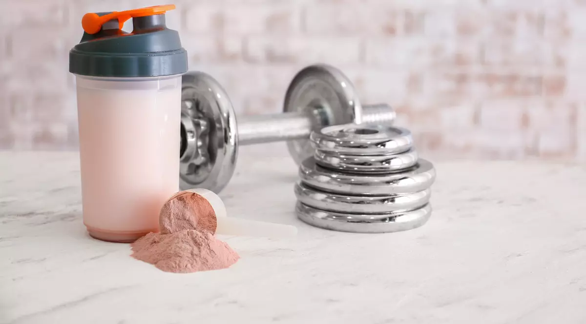 Ce sunt shake-urile proteice - Imagine cu un recipient în care a fost preparat un shake proteic, alături de o ganteră şi mai multe greutăţi