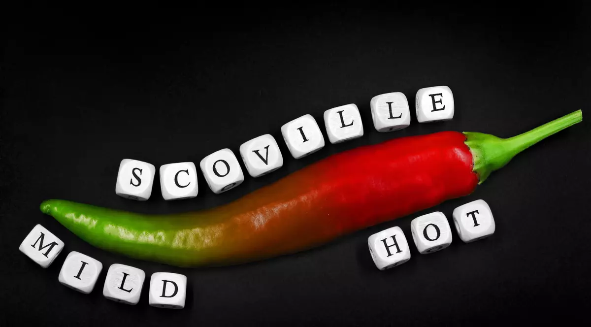 Ce este Scara Scoville și ce măsoară aceasta - Imagine cu un ardei jumătate verde, jumătate roşu, deasupra căruia scrie Scoville şi de desupt mild (în zona verde) şi hot (în zona roşie).