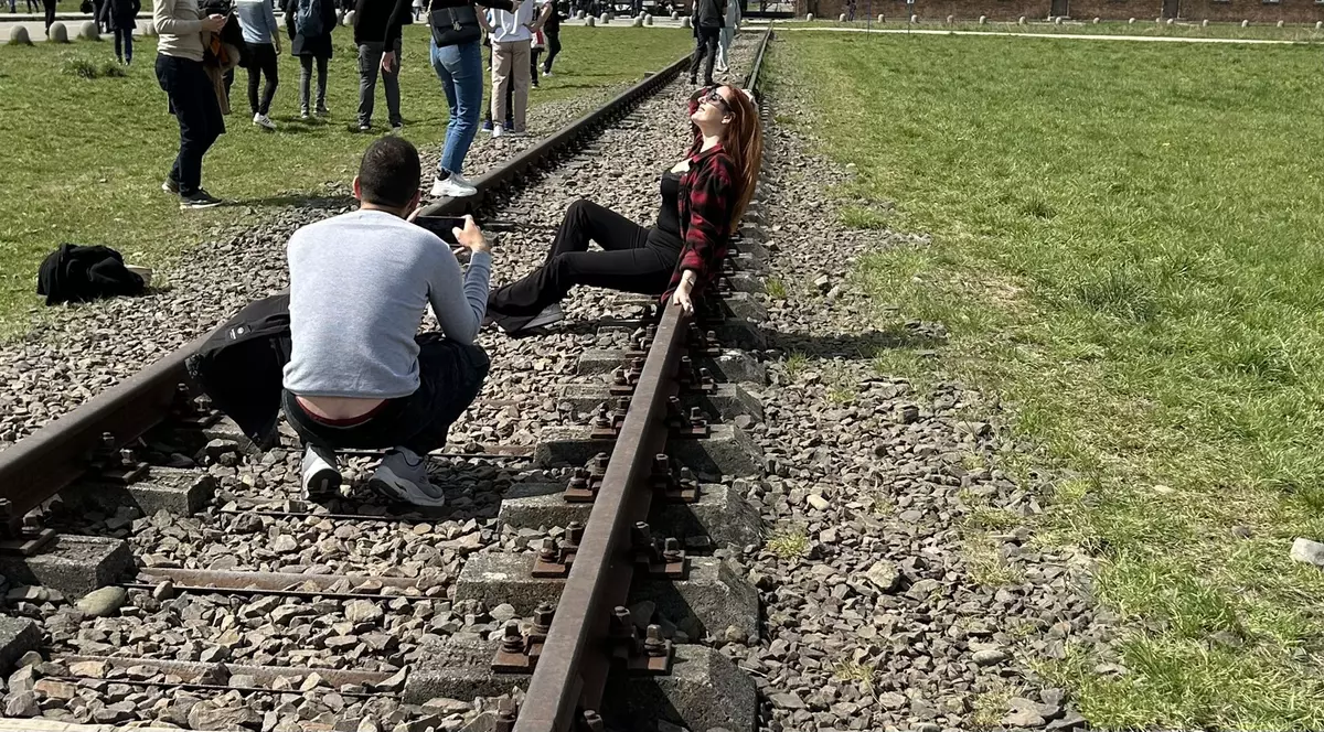 O tânără care pozează lasciv pe șinele de tren de la Auschwitz a stârnit indignare pe internet. „Nu întinați memoria lor”
