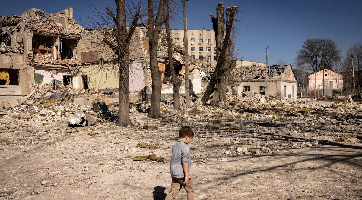 Un copil merge prin fața unei școli avariate din orașul Jitomir Foto: Profimedia