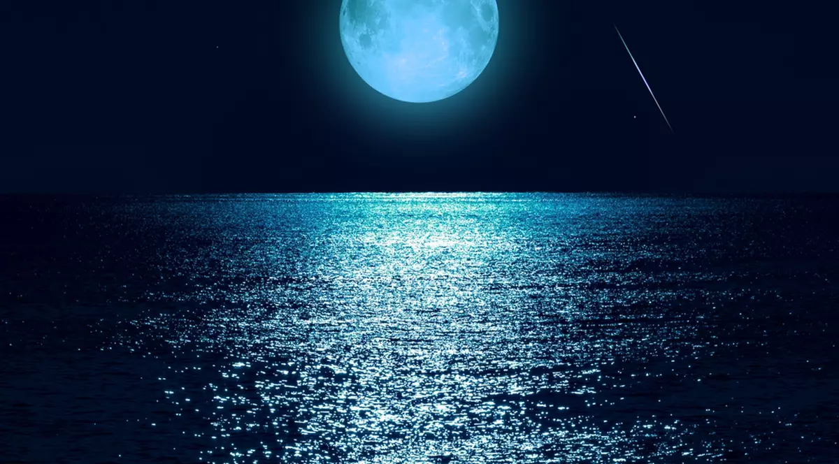 Luna plină din 30 august, o Superlună Albastră în zodia Peștilor - Imagine cu o lună plină deasupra unui peisaj marin, într-o lumină cu tentă albăstruie.