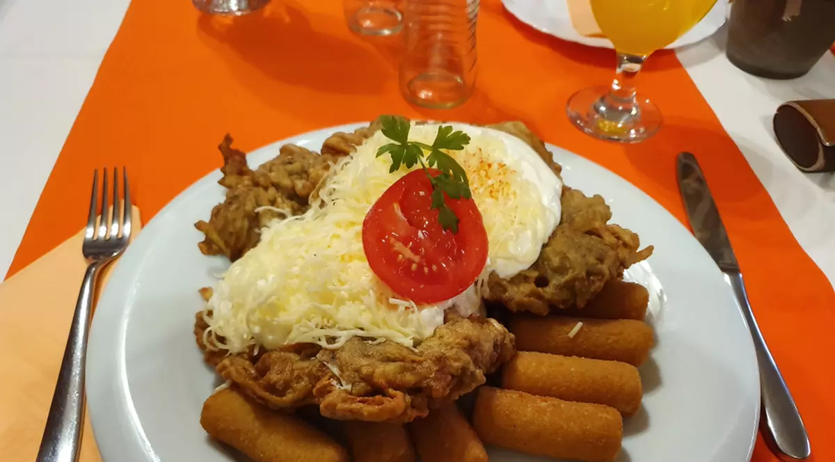 Mátrai borzaska - reţetă ungurească de şniţel - Imagine cu un şniţel matrai borzaska pe un pat de crochete, totul pe o farfurie întinsă.
