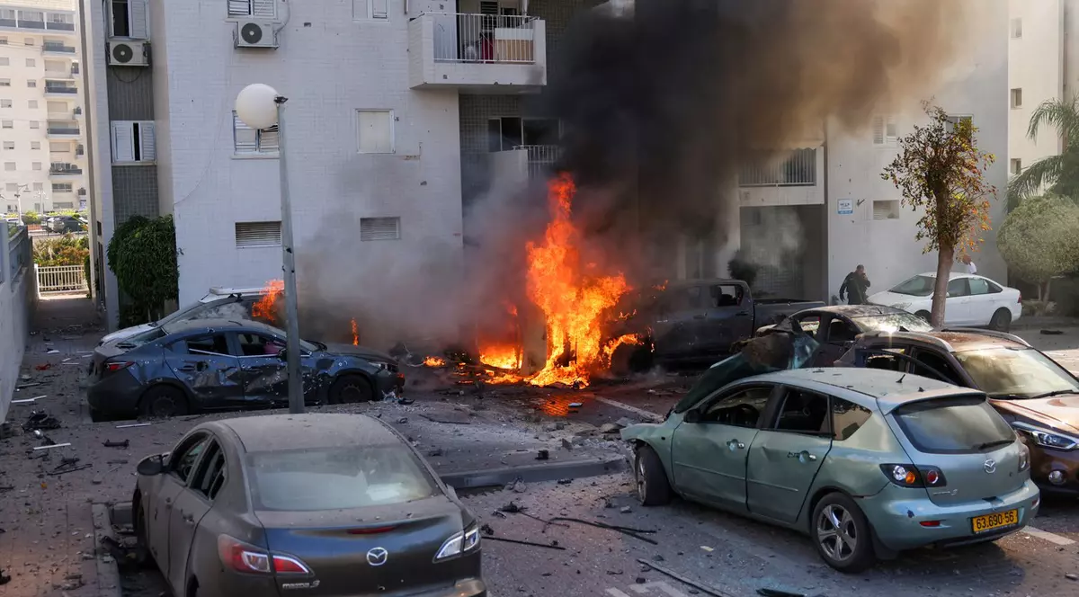 Forțele de securitate israeliene stau lângă mai multe mașini cuprinse de flăcări, în urma atacului lansat din Gaza, asupra orașului Ashkelon, aflat în sudul Israelului Foto: Profimedia