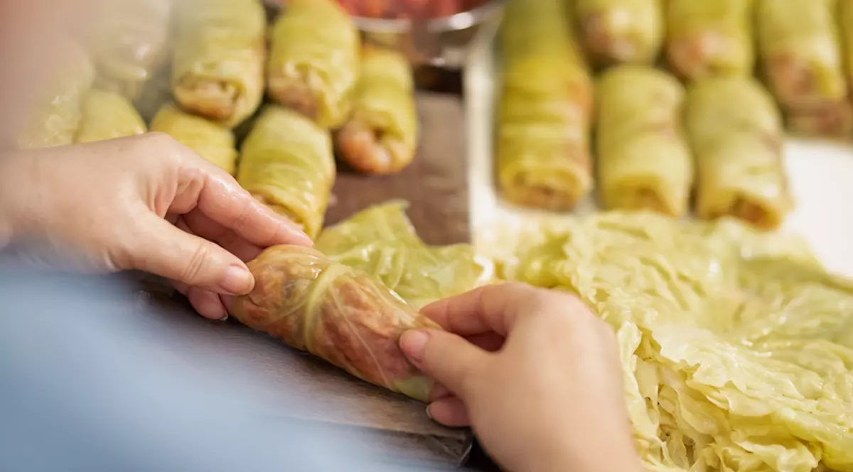 Reţetă sârbească de sarmale - Imagine cu o femeie care rulează sarmale