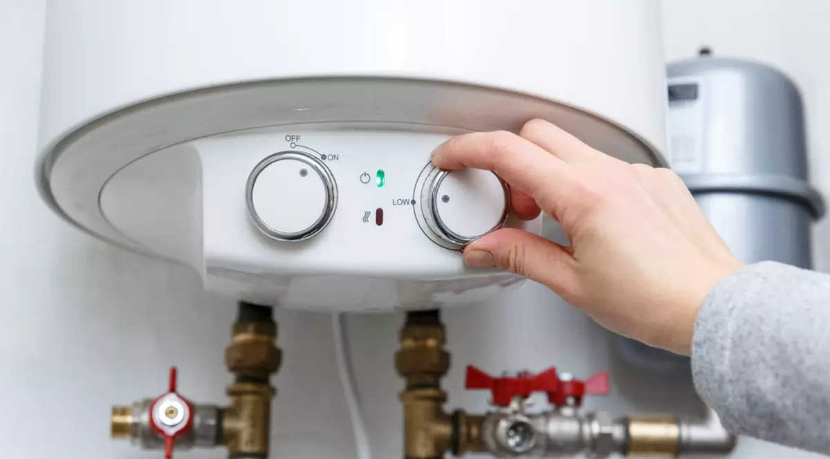 Diferența dintre boiler și instant electric - Imagine cu mâna unei femei care reglează temperatura la un aparat de încălzire