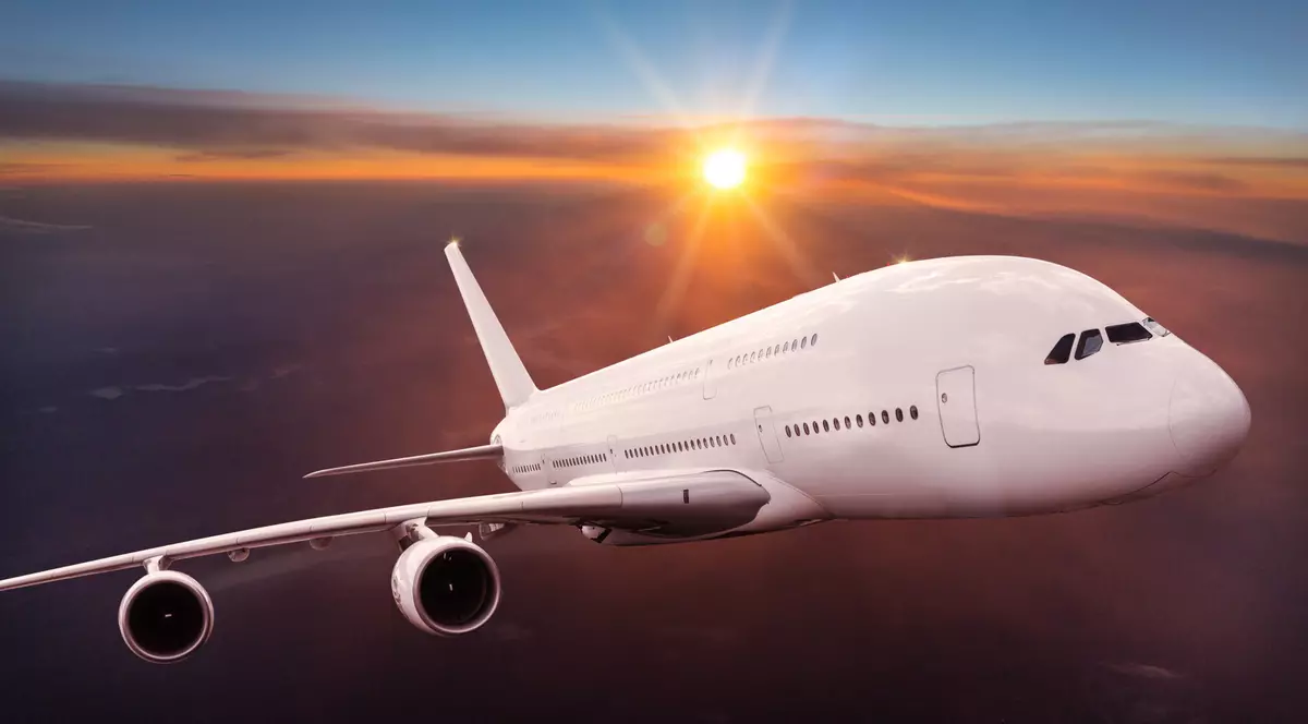 De ce, în general, avioanele sunt vopsite în alb - Imagine cu un avion vopsit în alb, ridicându-se deasupra norilor.