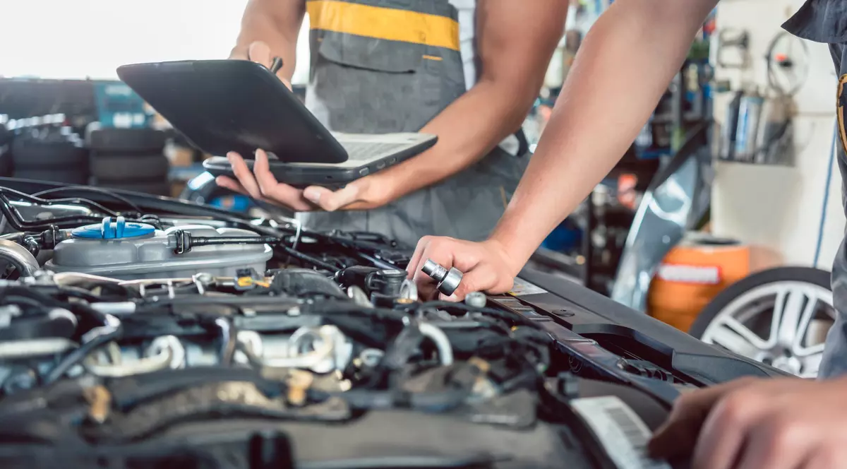 Cum să întreții o mașină corect. Ce trebuie schimbat și după câți kilometri - Imagine cu doi mecanici care veritifică o maşină cu un soft de test