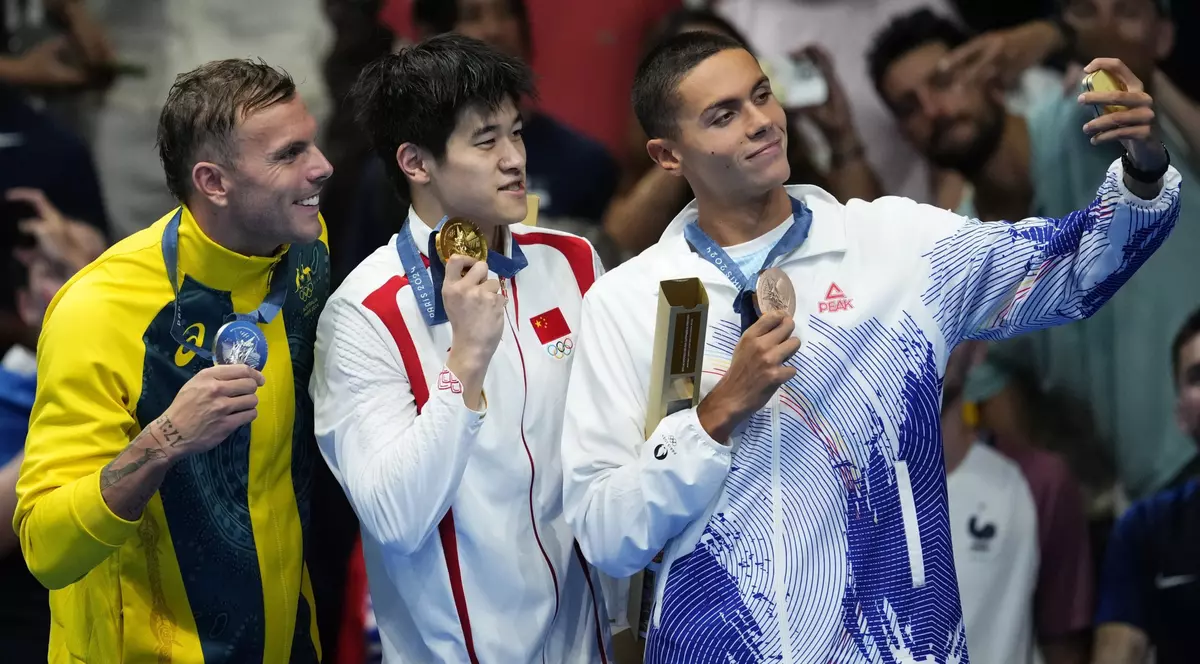 Medaliatul cu aur Pan Zhanle, din China, medaliatul cu argint Kyle Chalmers, din Australia, și medaliatul cu bronz David Popovici, pe podiumul de la JO 2024 după proba de 100 m liber Foto Profimedia