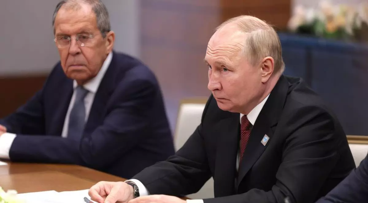 Președintele Rusiei, Vladimir Putin, în dreapta, alături de ministrul rus de Externe, Serghei Lavrov, în stânga, stau la o masă mare și discută