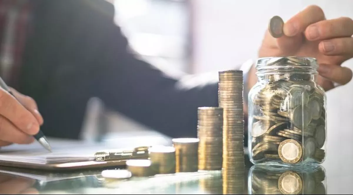 Un bărbat pune bani într-un borcan. Foto: Profimedia