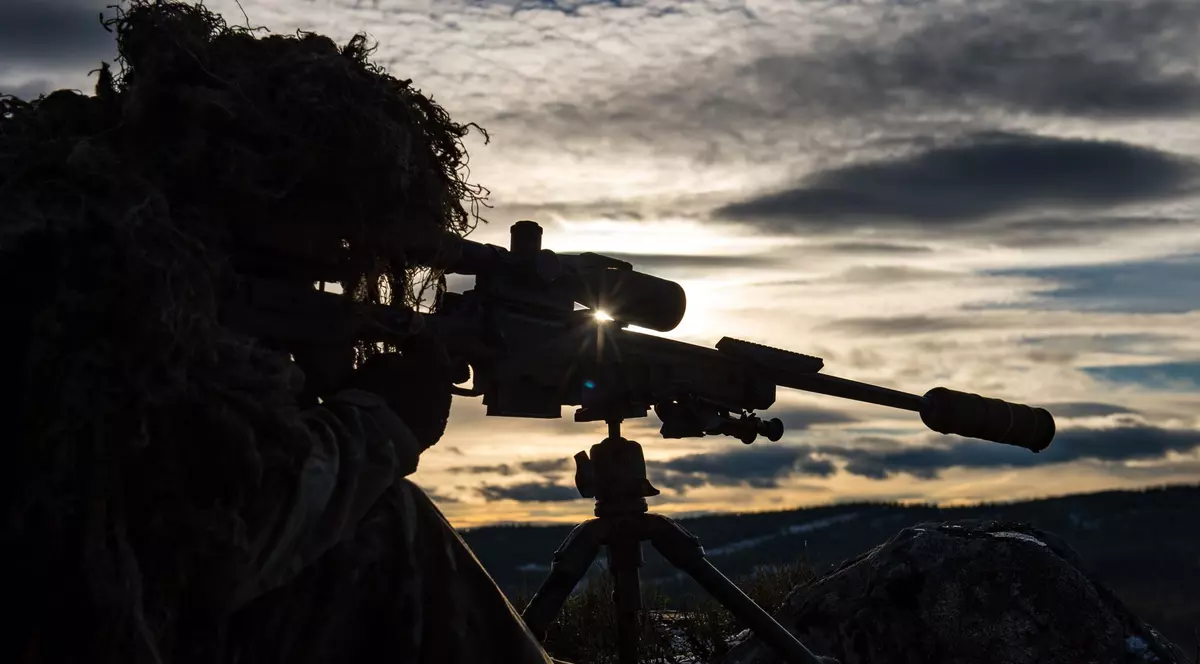 Bărbat care se pregătește să folosească o armă cu lunetă.