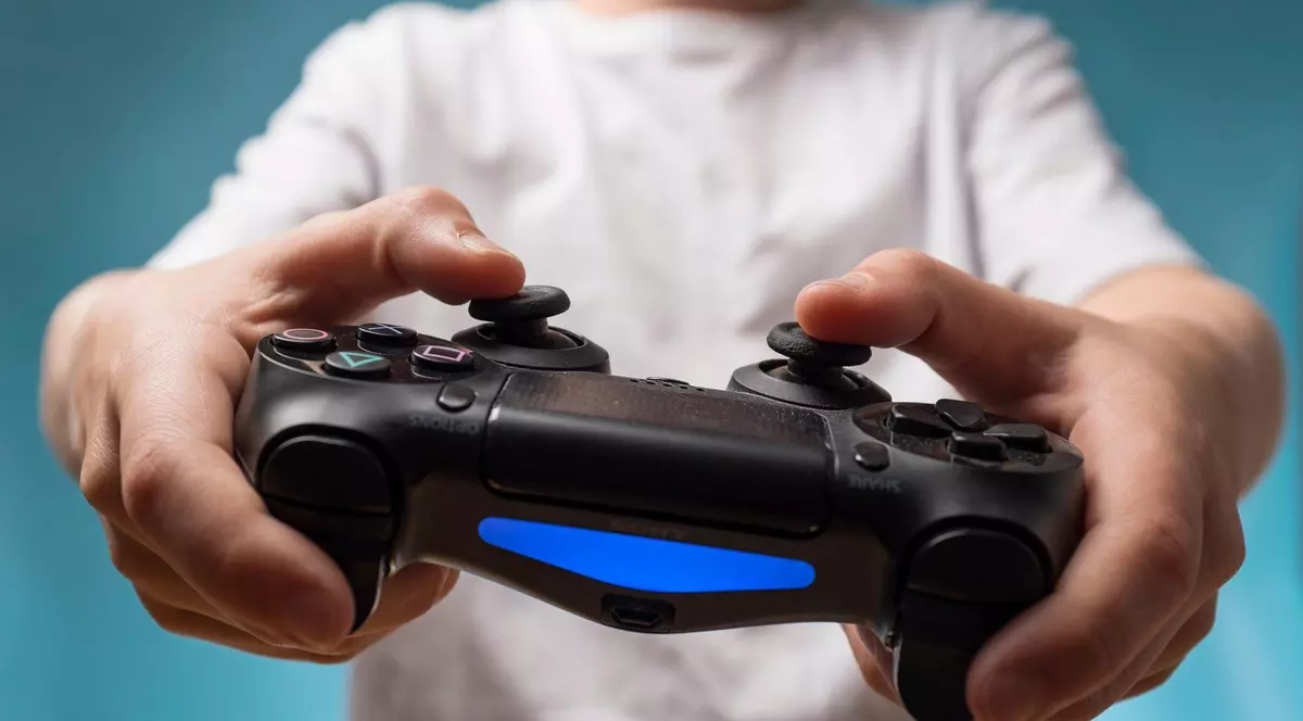 Copil care ține în mâini un controller Playstation.