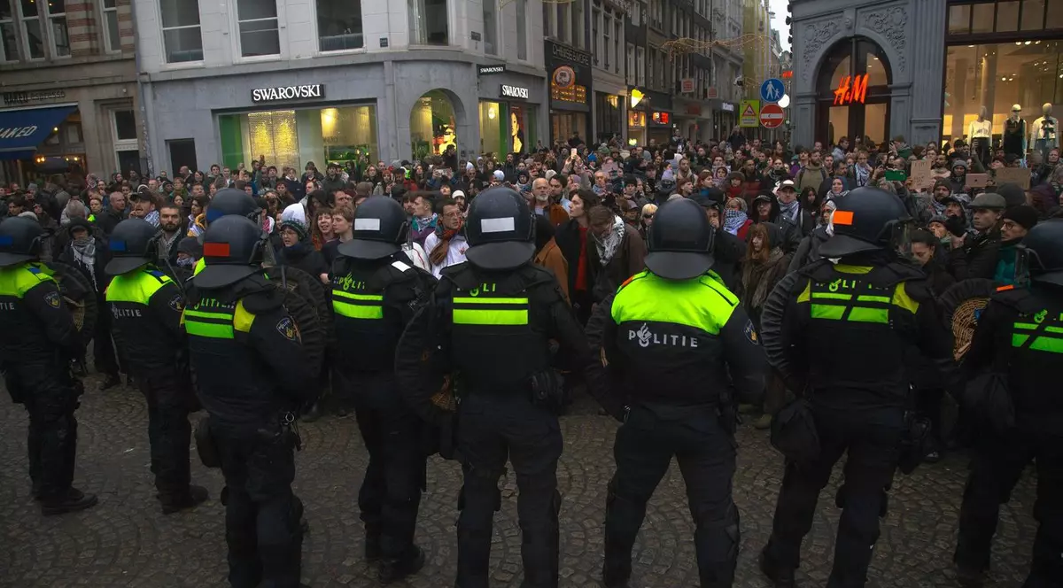 Ofițeri de poliție stau în linie în timp ce demonstranții pro-palestinieni se adună în Piața Dam, Amsterdam, duminică, 10 noiembrie 2024