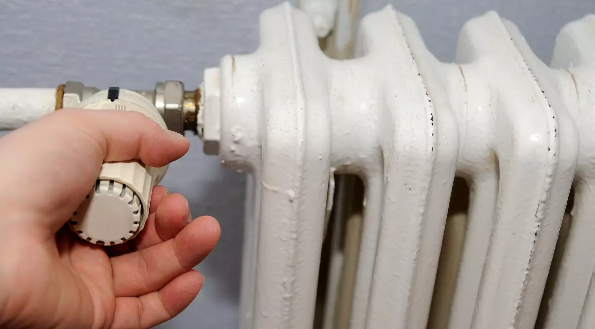 Un bărbat este cu mâna pe repartitorul de la calorifer. Prețul gigacaloriei s-a scumpit în Iași