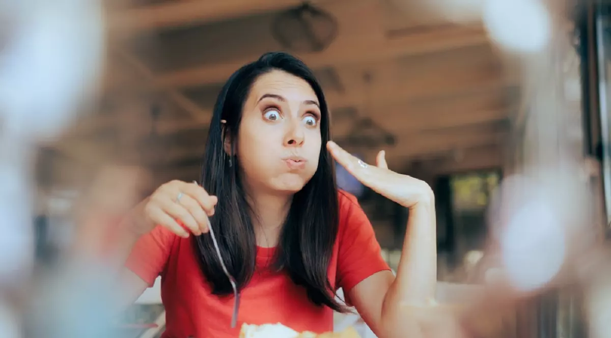 O femeie brunetă mananca dintr-un preparat foarte picant