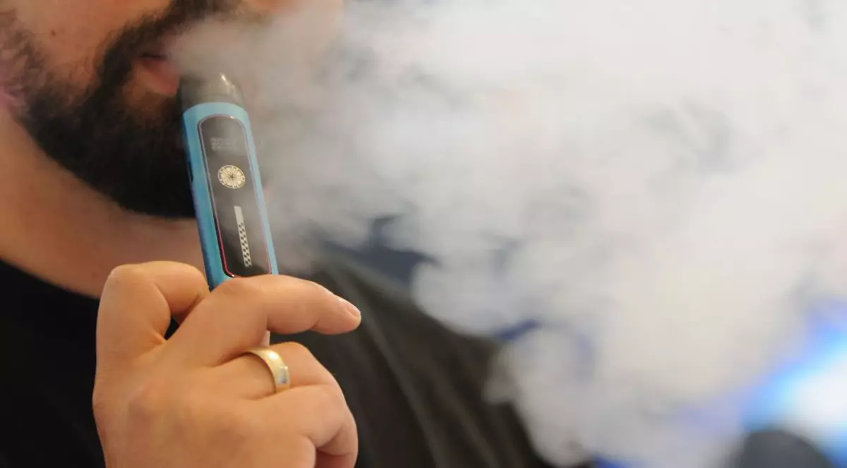 Tânăr care trage cu poftă dintr-o țigară electronică