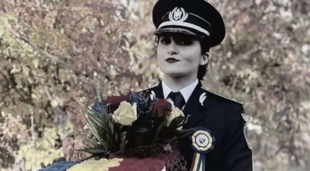 tanara politista in uniforma care tine in mana un buchet de flori