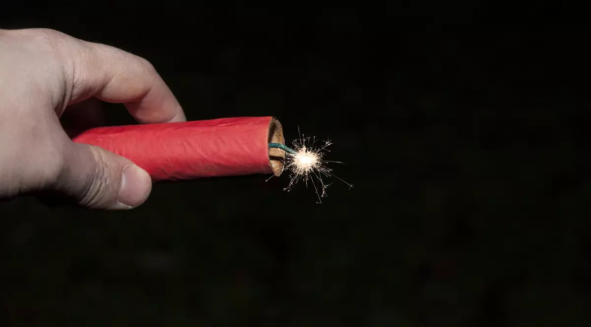 Poză cu o petardă ținută în mână de un bărbat